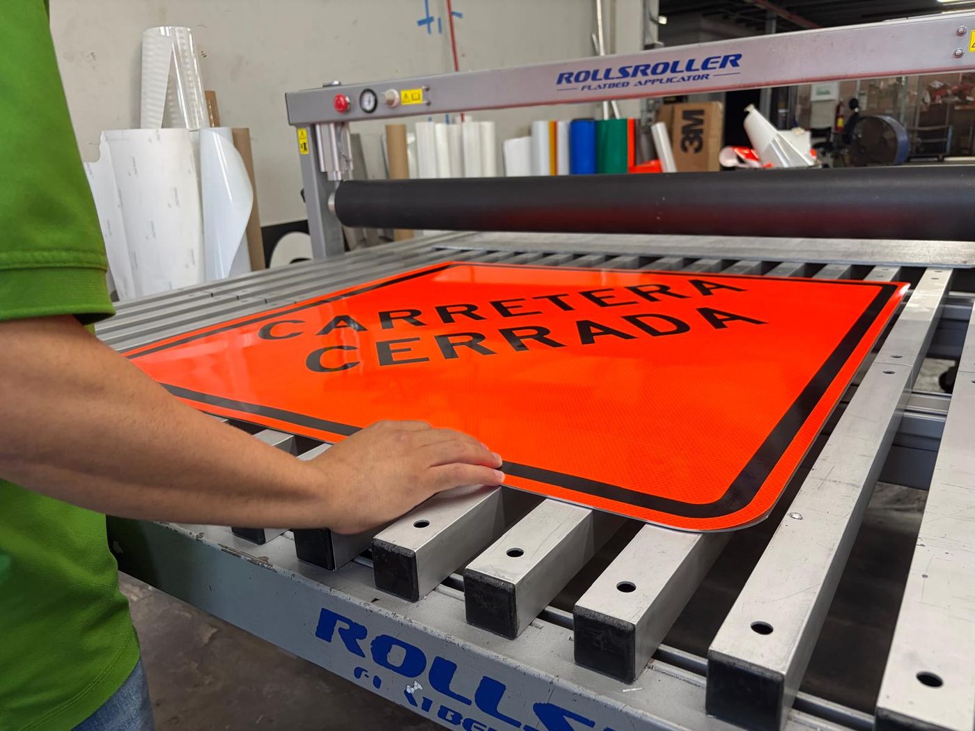Técnico de Caribbean Sign Supply aplicando lámina reflectiva a una señal de Carretera Cerrada en el taller